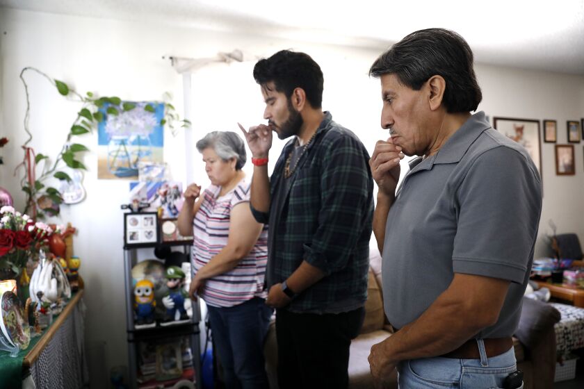 SANTA ANA, CALIFORNIA: Jonatan Gutierrez, 32, center, with his parents Pablo Gutierrez, 65, right, and Rocio Urzua, 54, pray together on Urzua's late father's birthday at home in Santa Ana, California on Friday, July 2, 2021. Medi-Cal expansion will offer relier to income eligible adults 50 and older regardless of immigration status. (Christina House / Los Angeles Times)