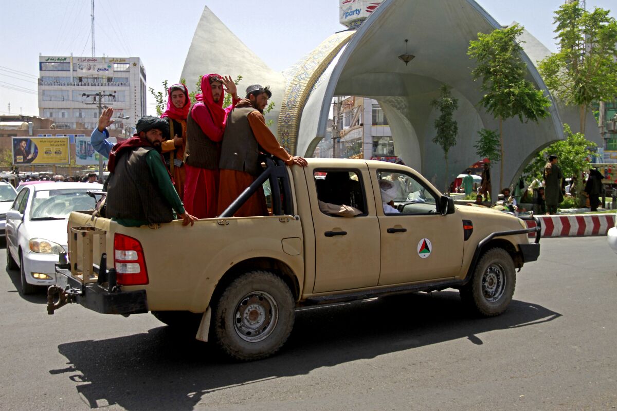 Taliban fighters ride in the back of a vehicle