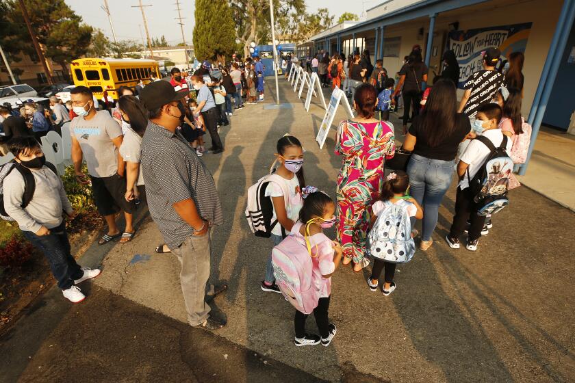 Students and parents wait in line to enter Normont Elementary School to celebrate the first day of in class instruction
