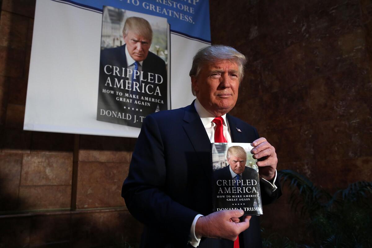 President Donald Trump holds a copy of his book "Crippled America: How to Make America Great Again" in 2015.