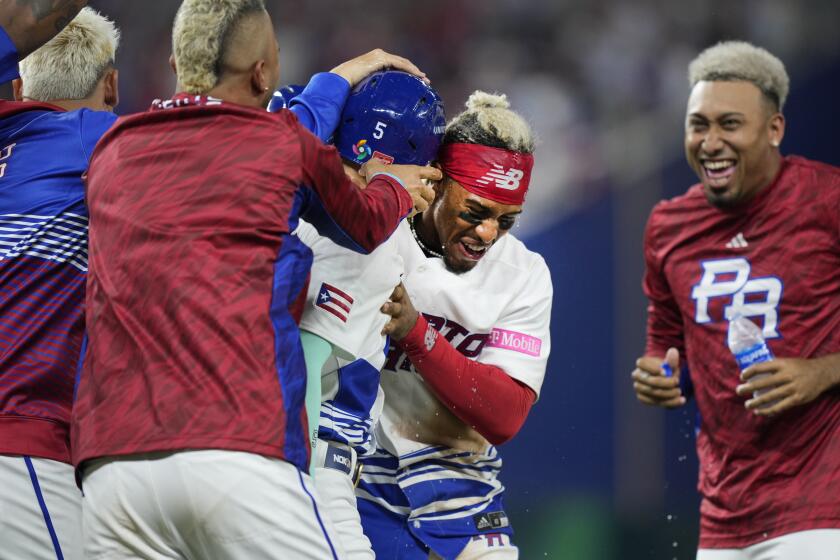 Los jugadores de Puerto Rico abrazan a Enrique Hernández (5) luego que éste dio el sencillo que remolcó a Martín Maldonado con la carrera que definió en el octavo inning la victoria 1-0 ante Israel en el Clásico Mundial de béisbol, el lunes 13 de marzo de 2023. (AP Foto/Wilfredo Lee)