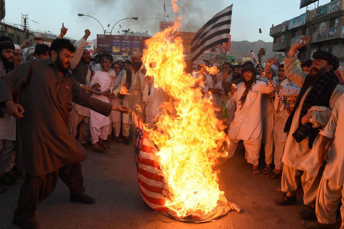 Pakistani Sunni Muslim supporters of a hard-line pro-Taliban party torch a U.S. flag during a protest of the drone strike that killed the Taliban's leader.