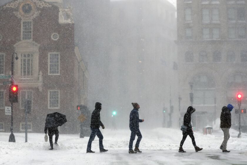 People cross Congress Street, Saturday, Jan. 29, 2022, in Boston. Forecasters watched closely for new snowfall records, especially in Boston, where the heaviest snow was expected late Saturday. (AP Photo/Michael Dwyer)