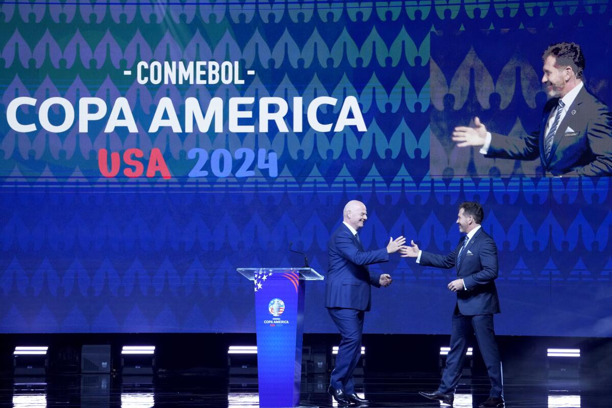 CONMEBOL President Alejandro Dominguez, right, greets FIFA President Gianni Infantino on stage.