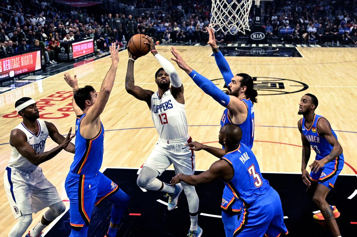 Clippers forward Paul George puts up a shot amid a pack of Thunder defenders during a game Nov. 18 at Staples Center.