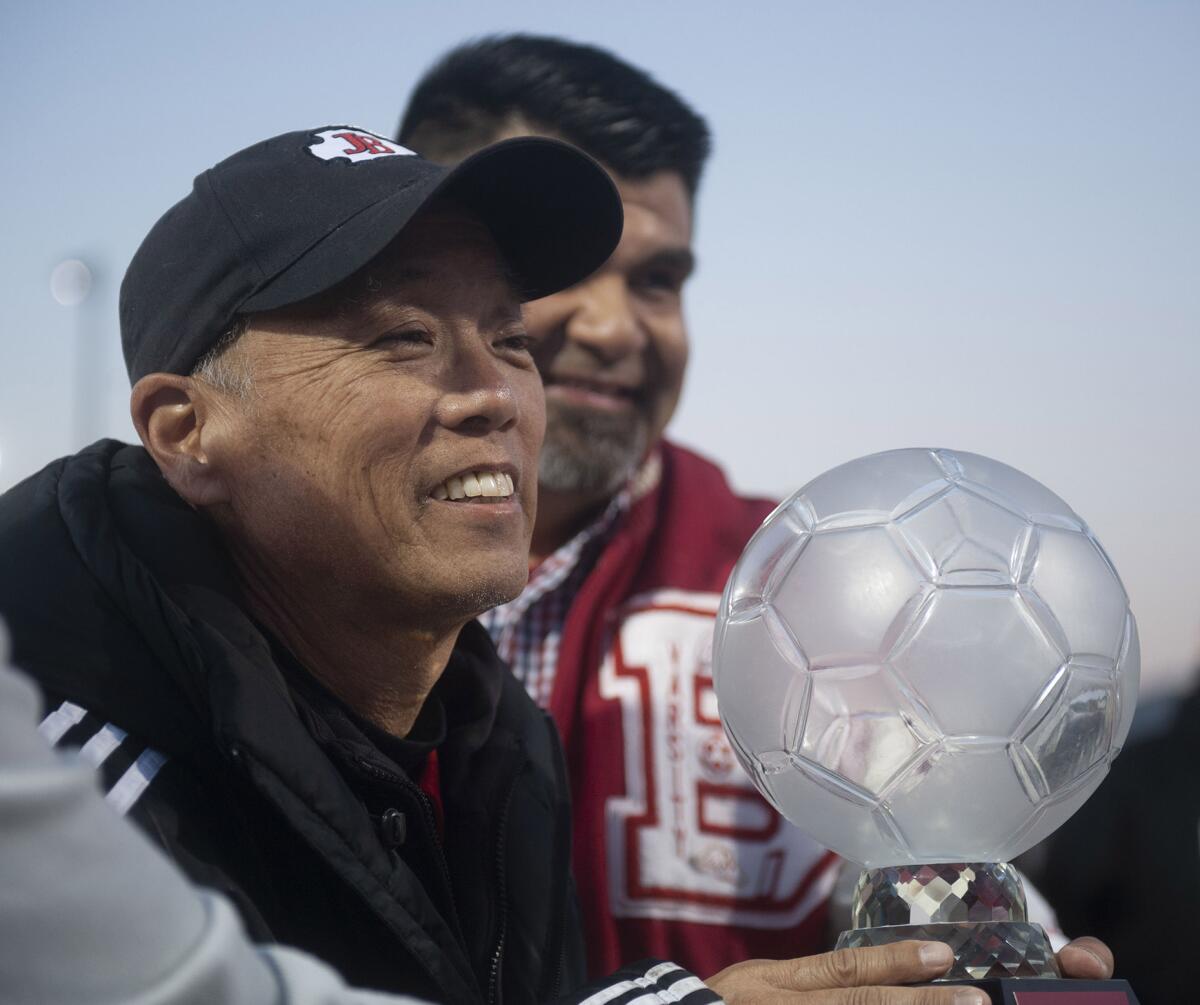 Former Burroughs High boys soccer coach Mike Kodama holds up a crystal soccer ball presented to him during Thursday's tribute to his time with the team. (Photo by Miguel Vasconcellos)