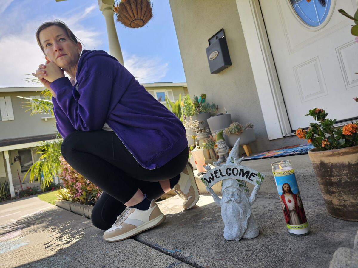 Tori Athey sits next to a garden gnome made by her neighbor, the victim of a shooting in Huntington Beach.