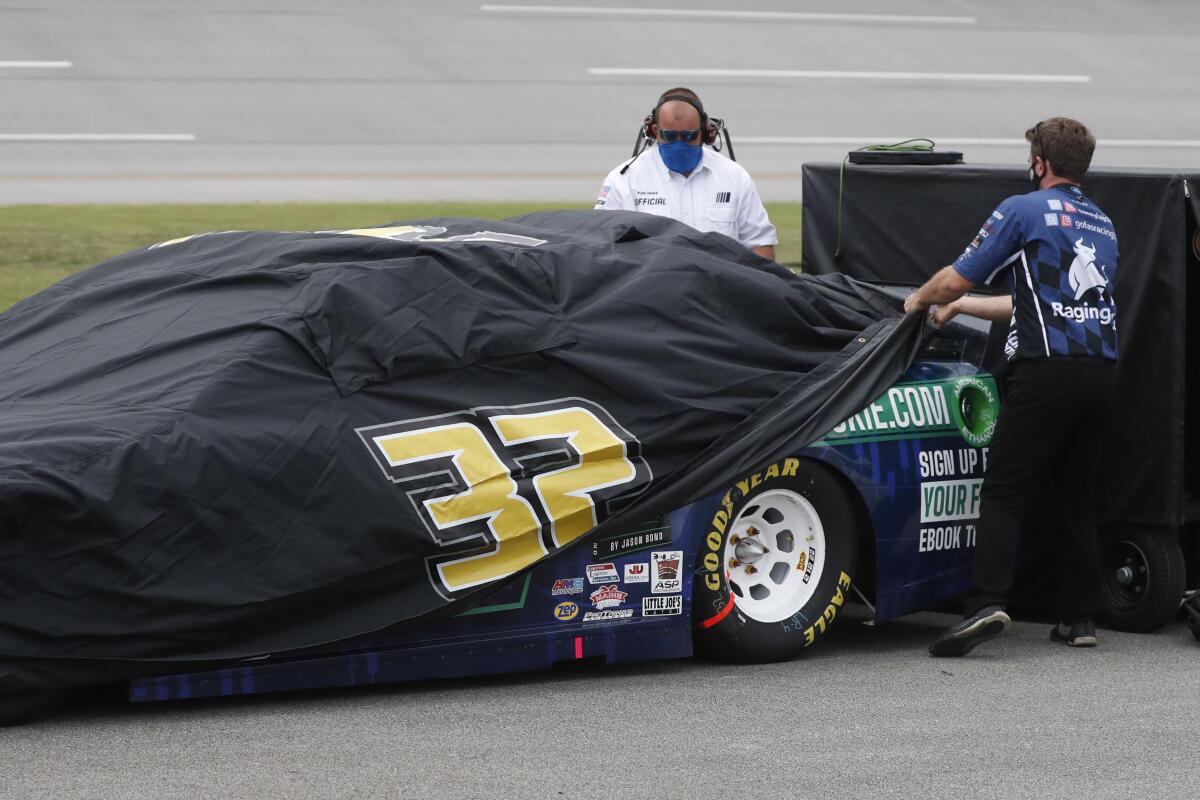 Crews cover Corey LaJoie's car during a rain delay at Talladega Superspeedway on Sunday.
