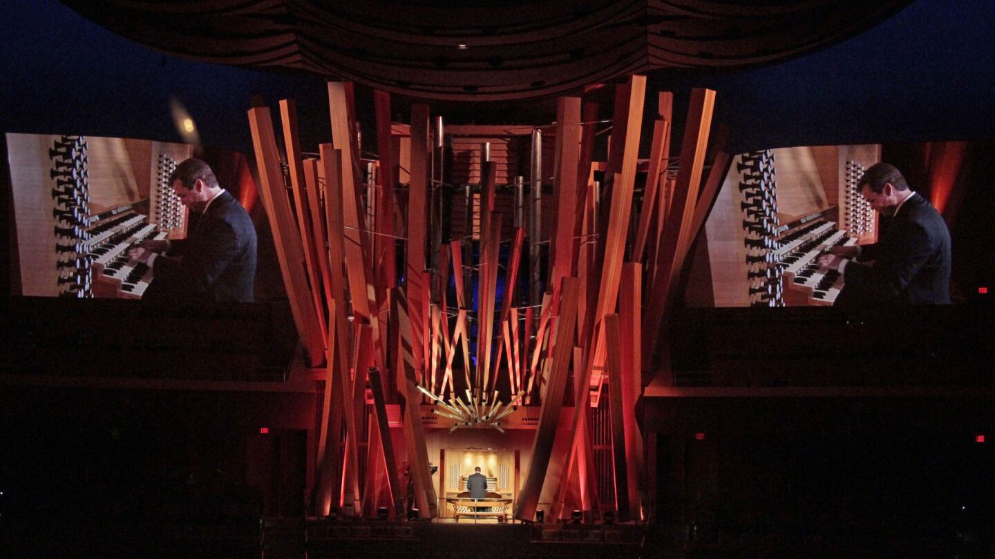 Ken Cowan amid the pipes of the Concert Hall's organ, with video projections of him playing off to the sides.
