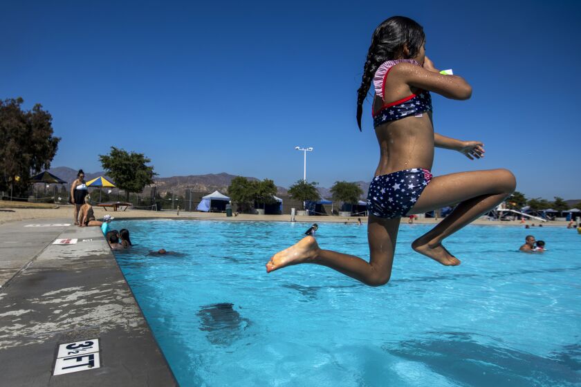 LAKE VIEW TERRACE, CA - JULY 11, 2022 - Emma Aguilar, 6, of Pacoima, CA leaps into the 1.5-acre swimming lake at the Hansen Dam Aquatic Center as temperatures reached 90 degrees in Lake View Terrace on July 11, 2022. The weather is expected to get hotter over the coming weekend. (Francine Orr/ Los Angeles Times)