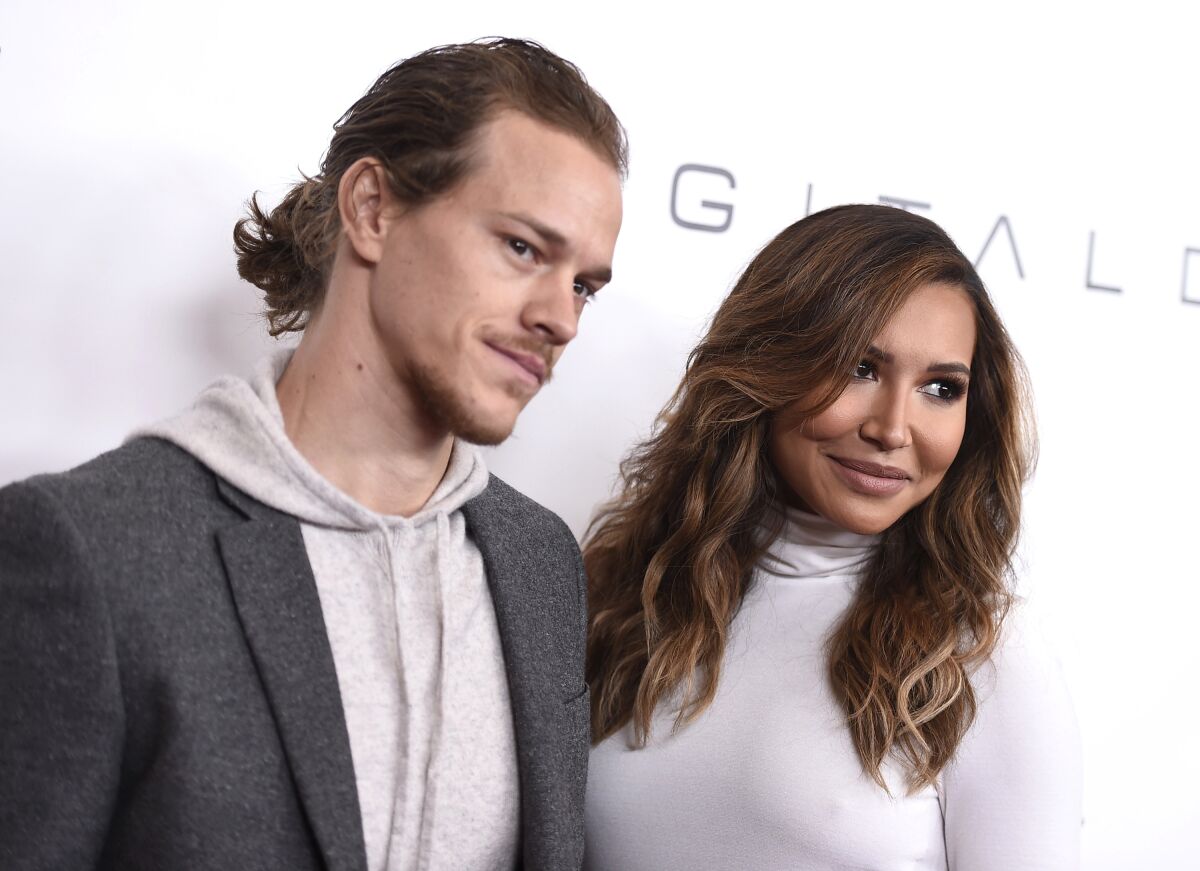 A man in a gray suit posing with a woman in a white turtleneck