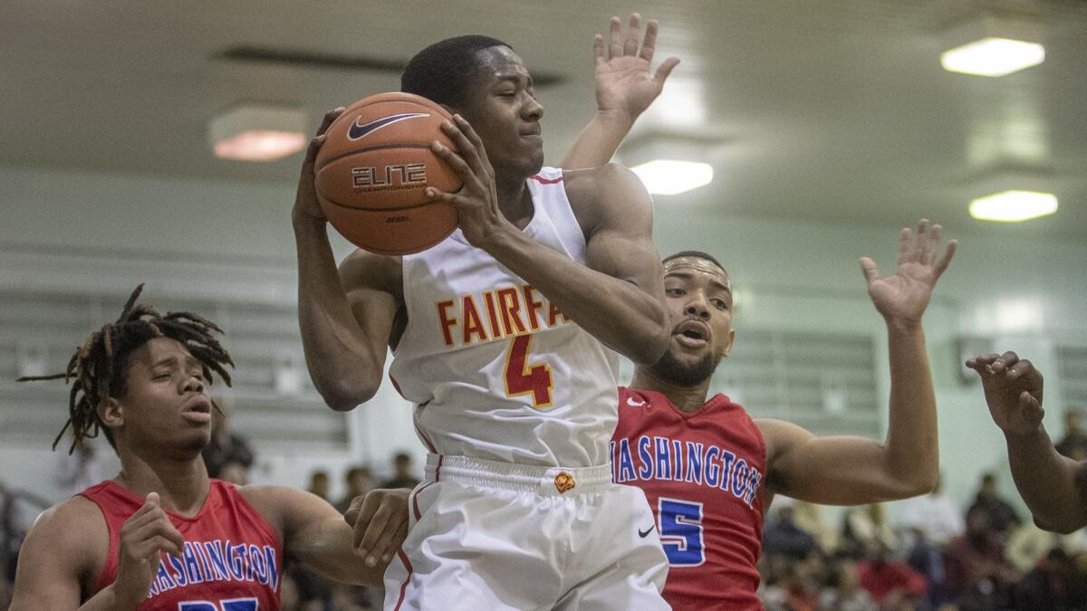 Fairfax's Ronald Mitchell, center, comes down with a defensive rebound away from Washington Prep's DeShawn Johnson left, and Hassan Hughey, right, in the City Section Open Division basketball semifinals at Venice High School.