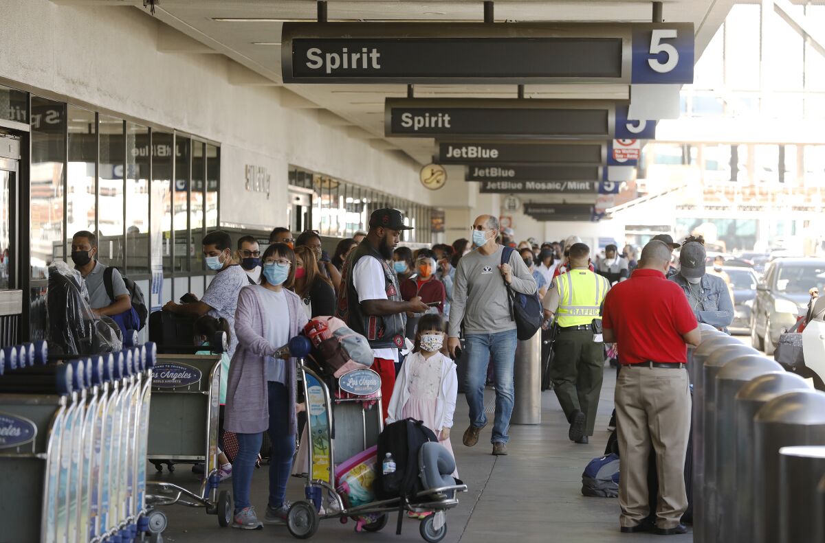 A  large crowd of passengers waits outside an airport terminal after canceled flights.