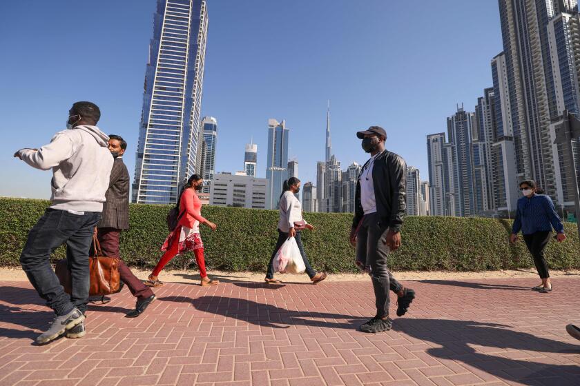 Employees walk to work on the first working Friday in the Gulf Emirate of Dubai, on January 7, 2022. - The United Arab Emirates has changed its workweek, making Sunday which is a work day in much of the Muslim world, part of the weekend. (Photo by Karim SAHIB / AFP) (Photo by KARIM SAHIB/AFP via Getty Images)