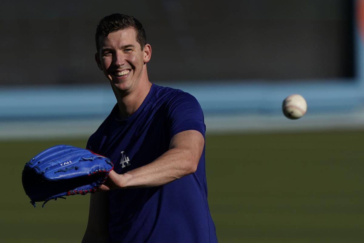 Walker Buehler smiles as he reaches to catch a baseball.