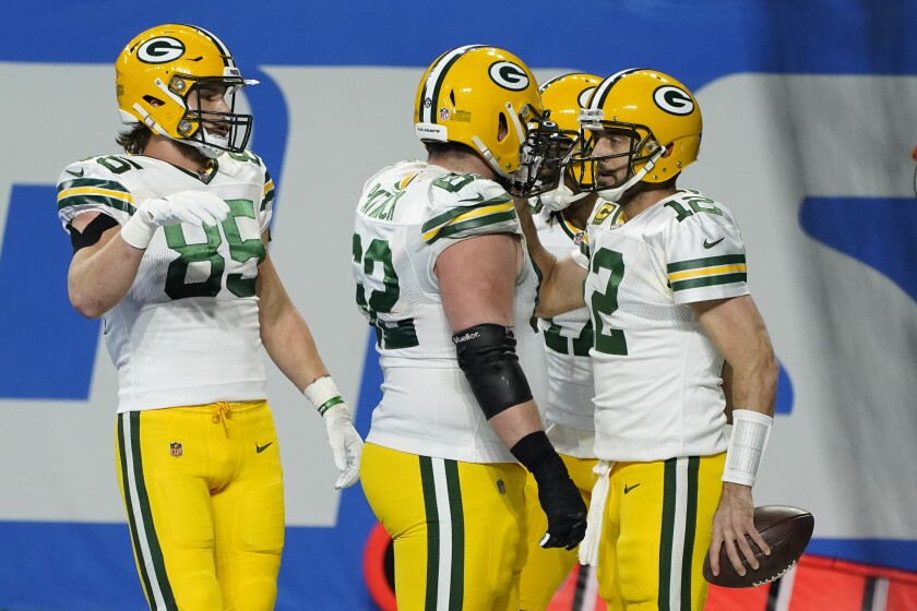 Green Bay Packers quarterback Aaron Rodgers, right, is congratulated by teammates after his 6-yard run for a touchdown during the second half of an NFL football game against the Detroit Lions, Sunday, Dec. 13, 2020, in Detroit. (AP Photo/Paul Sancya)
