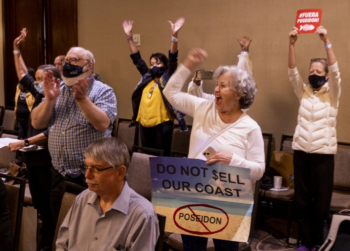 Audience members cheer and raise their hands at a meeting.