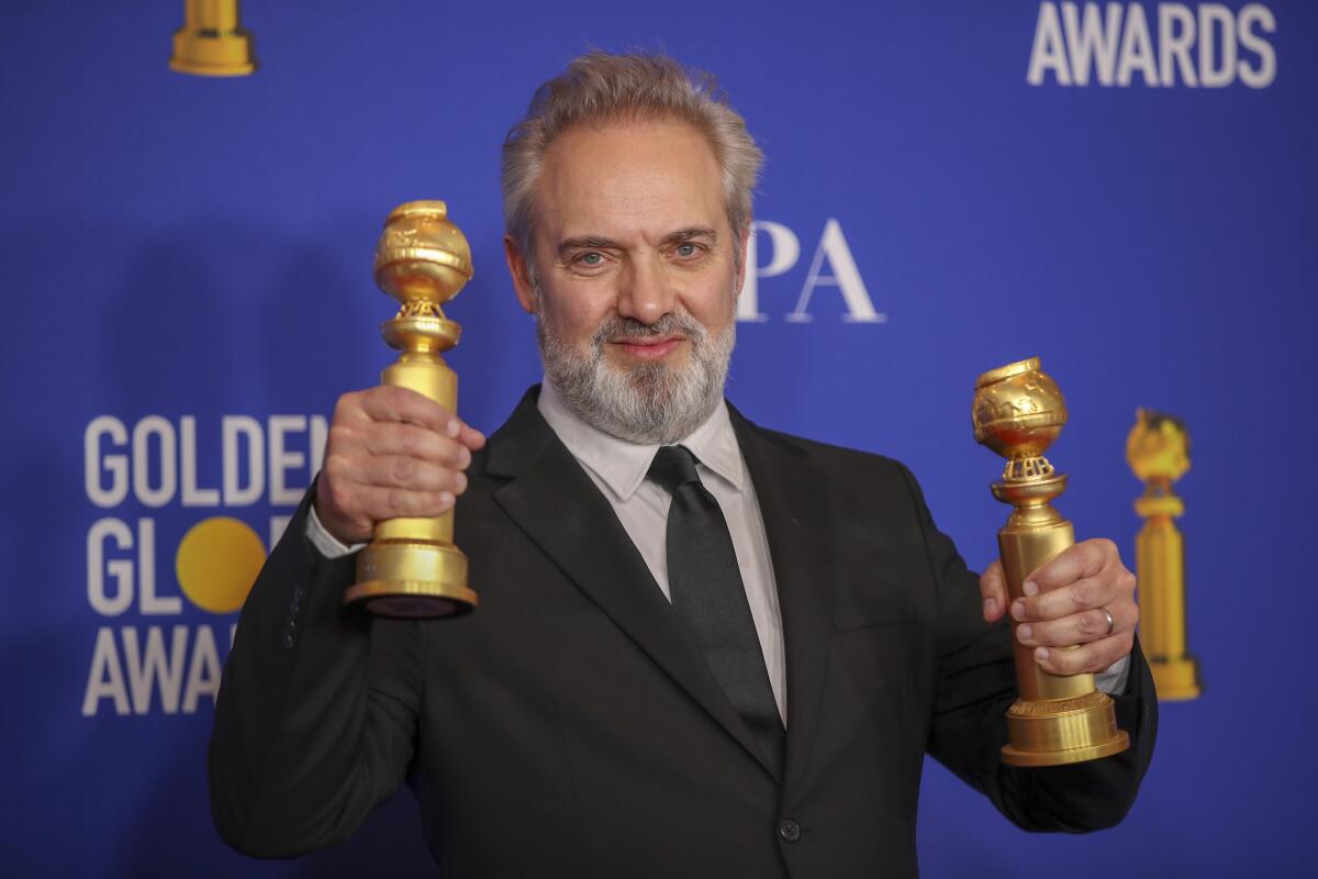 Sam Mendes holds up the Golden Globes he won for "1917."