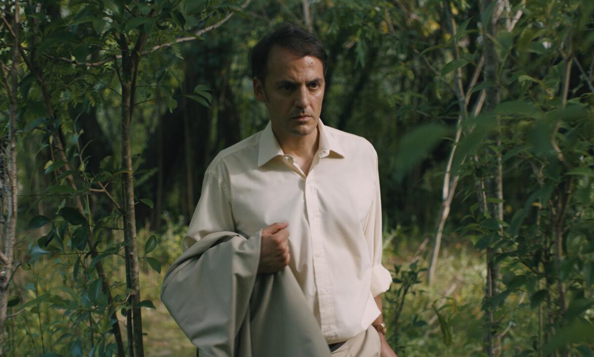 A well-dressed man walks through a wooded area in the movie "Azor."