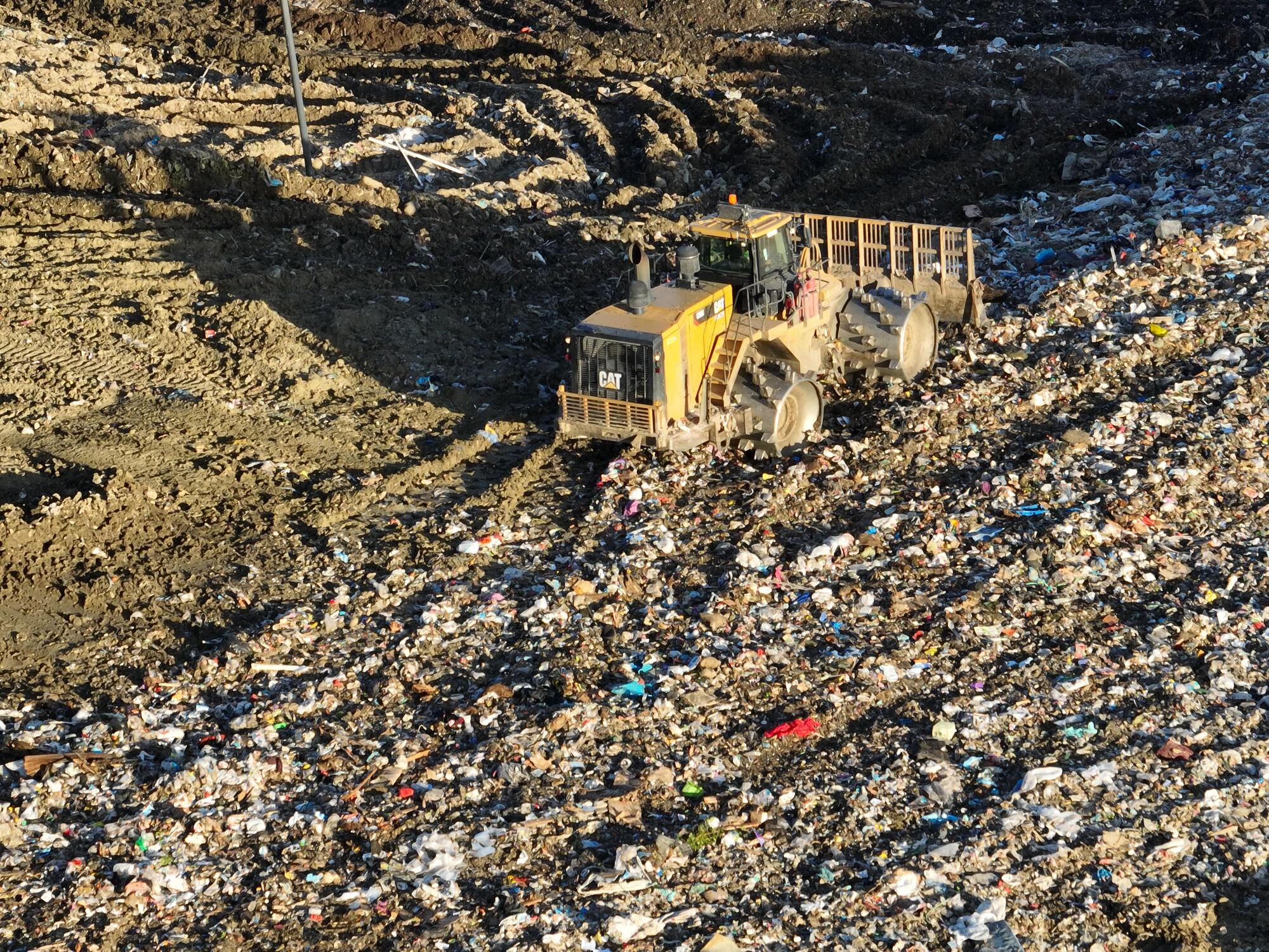 An  aerial view of heavy equipment spreading trash.