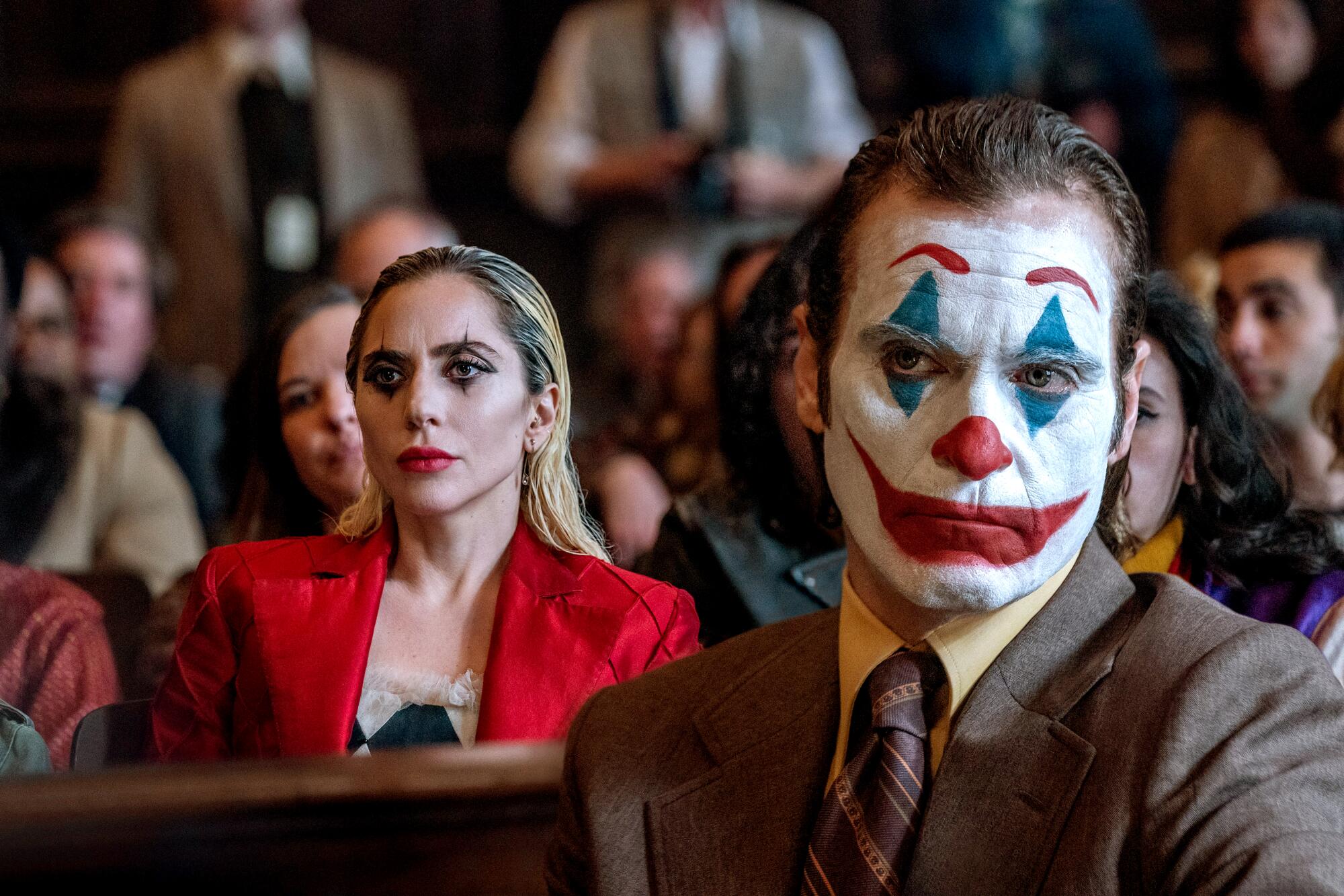 A man in clown makeup sits in front of a woman.