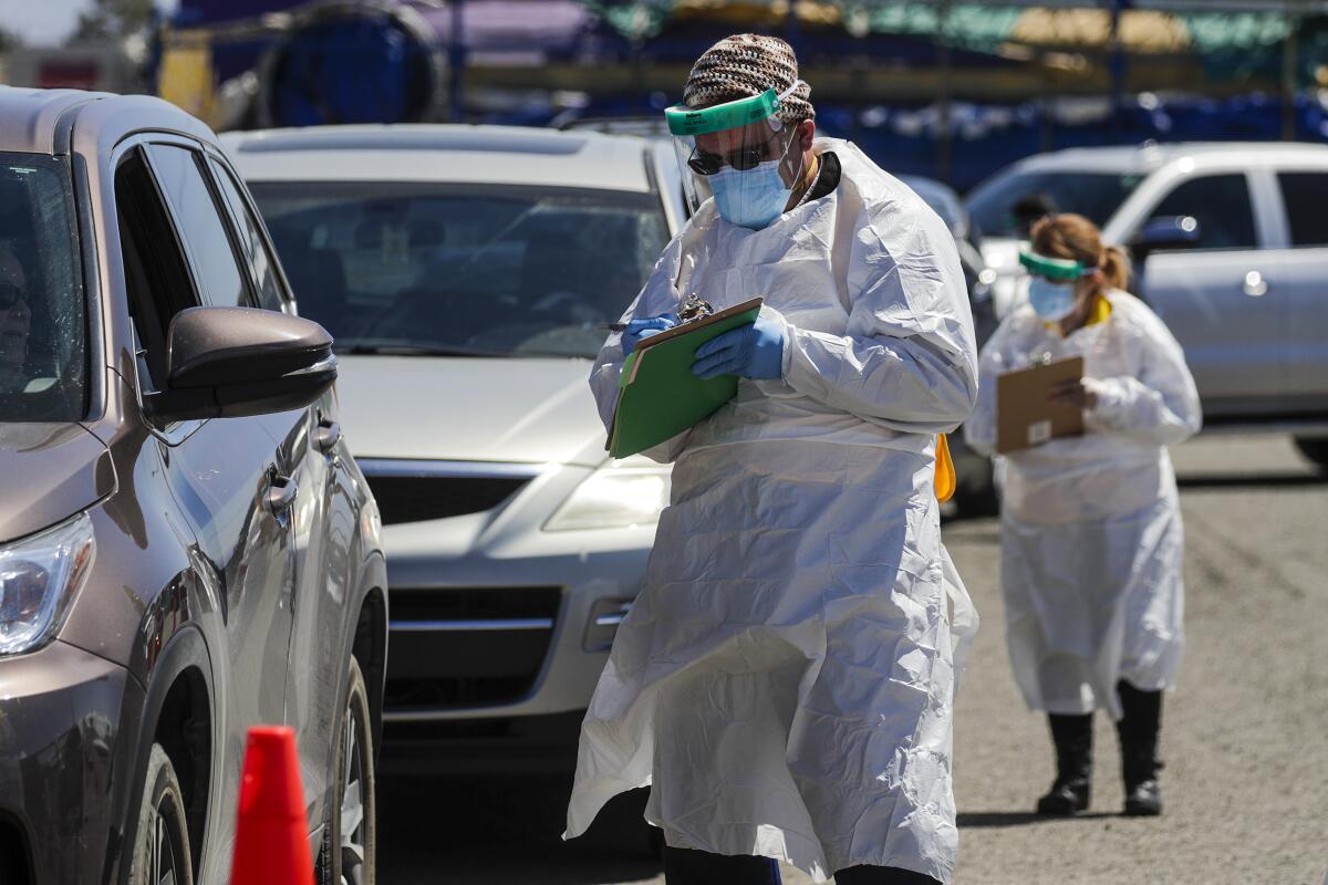 People wait in their cars at a virus test site in Victorville.
