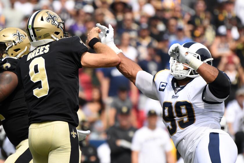 LOS ANGELES, CALIFORNIA SEPTEMBER 15, 2019-Rams defensive lineman Aaron Donald hits Saints quarterback Drew Brees in the hand in the 1st quarter at the Coliseum Sunday. Brees left the game after the play and never returned. (Wally Skalij/Los Angeles Times)