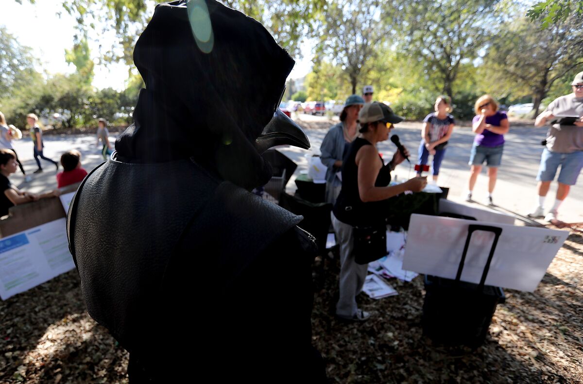 Robert Flynn, dressed as a 17th century plague doctor, joins people against coronavirus restrictions and vaccines in Redding.