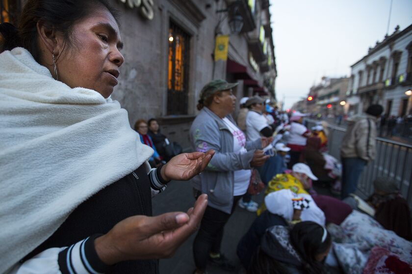Women pray along the Pope's route near the cathedral in Morelia, Michoacan.
