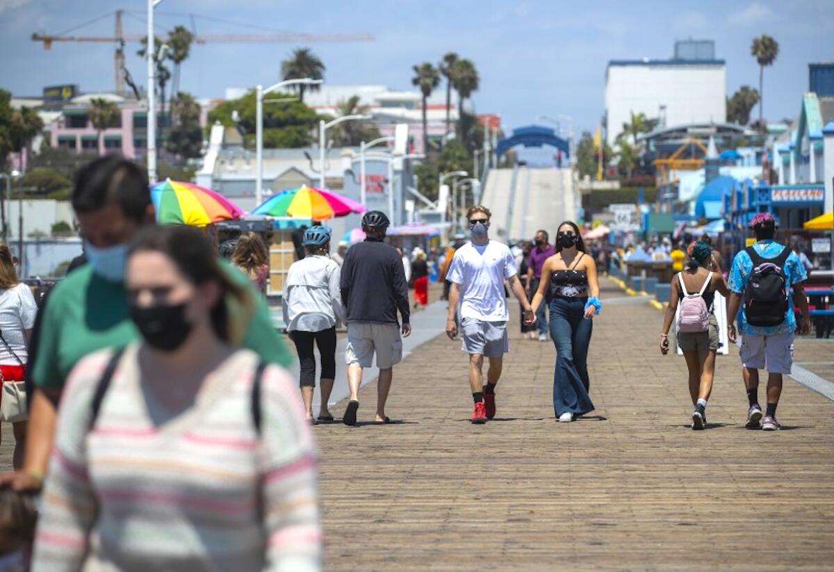 People in face masks walk on the Santa Monica Pier
