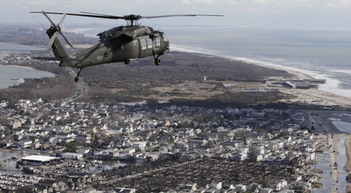 An Air National Guard helicopter flies above the Breezy Point neighborhood in New York where more than 100 homes, lower right, were burned to the ground during superstorm Sandy.