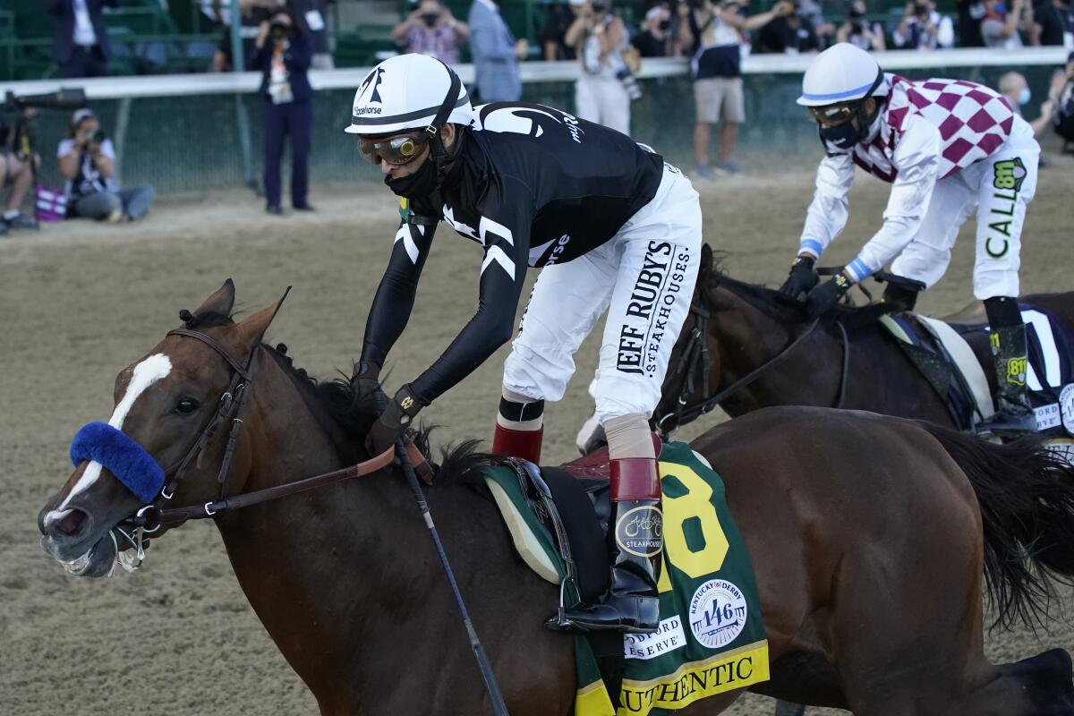 Jockey John Velazquez rides Authentic across the finish line, ahead of jockey Manny Franco and Tiz The Law.