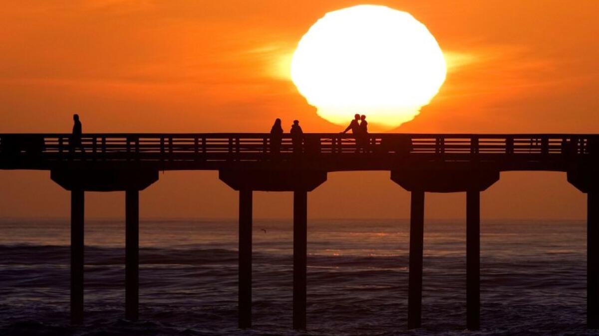 The sun sets behind the Ocean Beach Pier in San Diego after a big surf day.