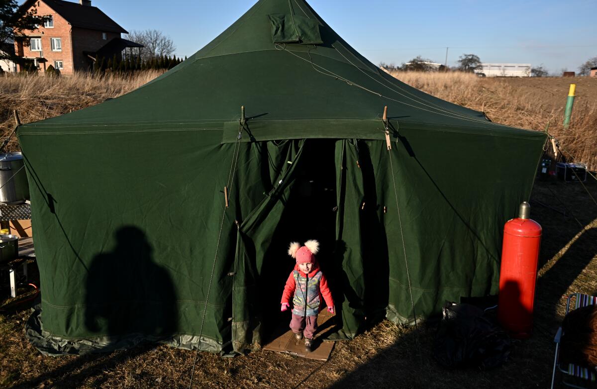 A young Ukrainian refugee plays around a tent used as a temporary shelter.