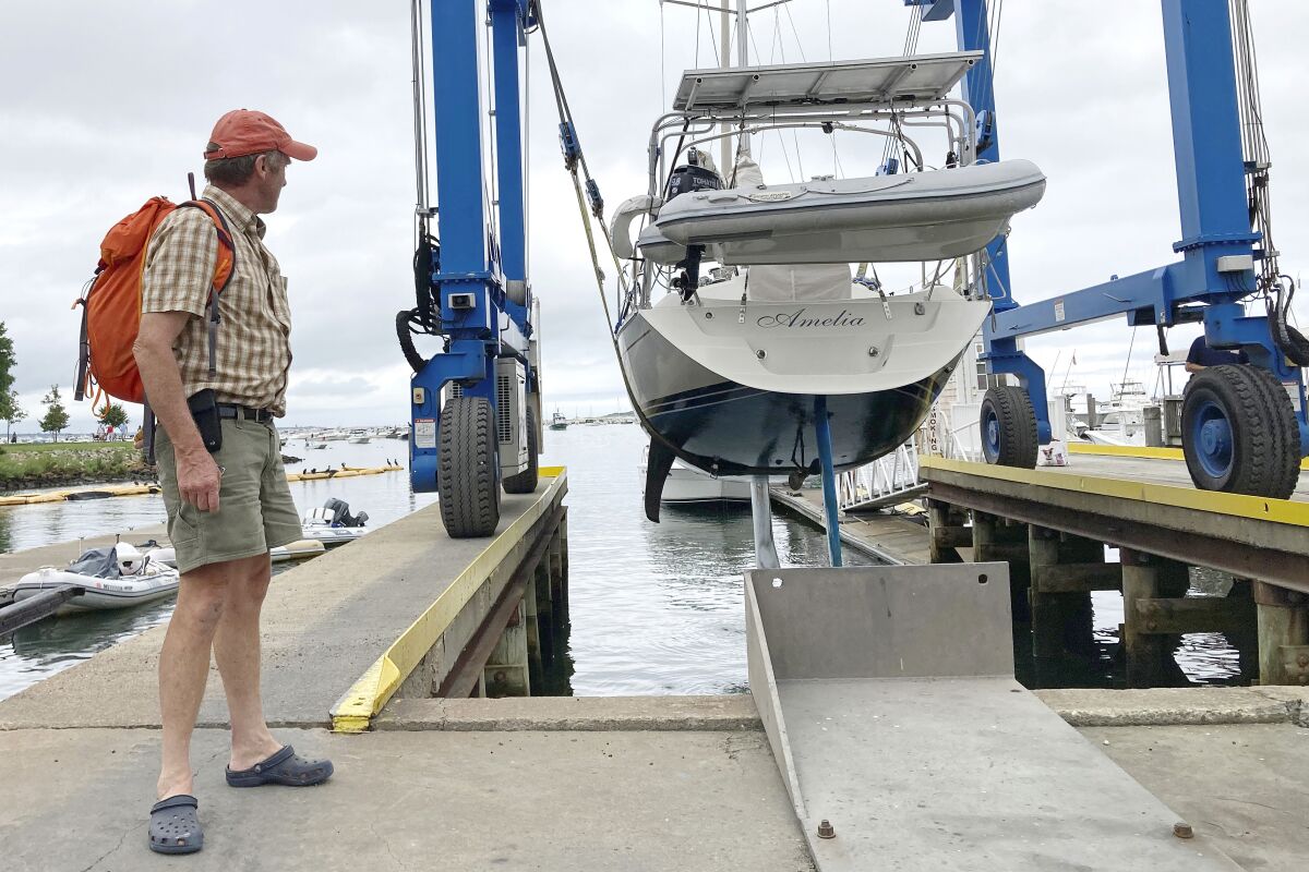 Robin Berthet watches as his sailboat is lifted out of the water.