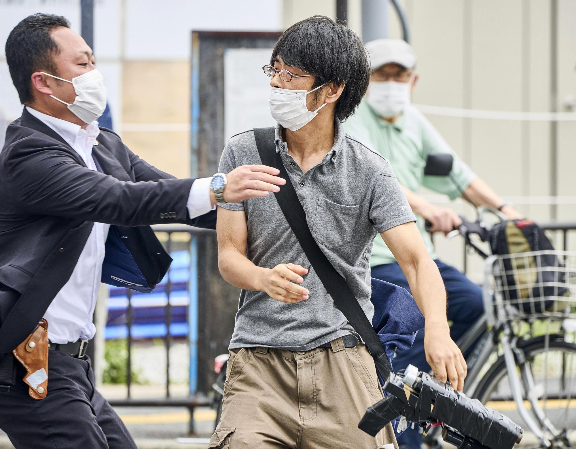 Tetsuya Yamagami, center, holding a weapon, is detained near the site of gunshots in Nara, western Japan