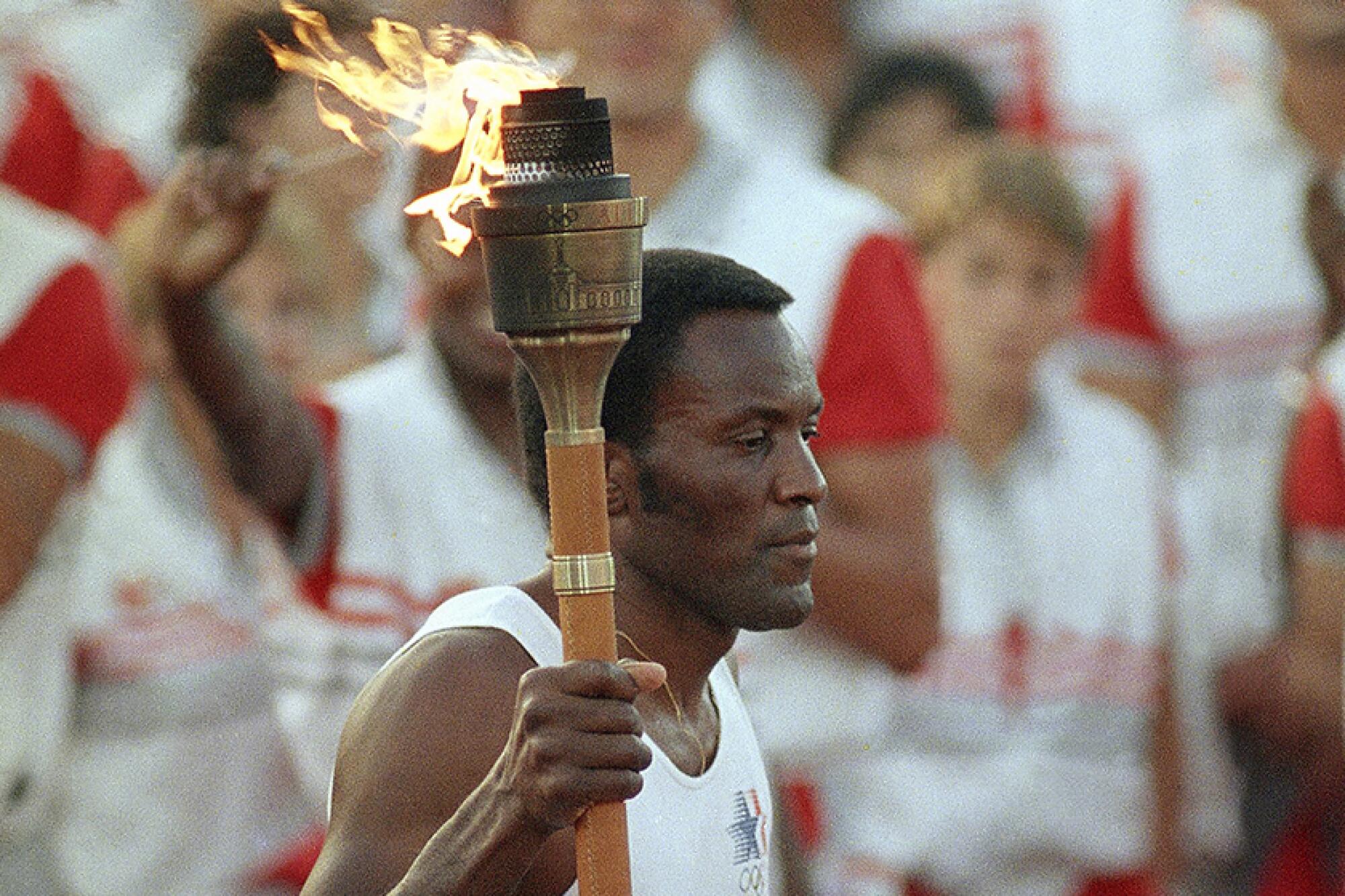 Rafer Johnson carries the Olympic torch through the Los Angeles Memorial Coliseum in 1984.
