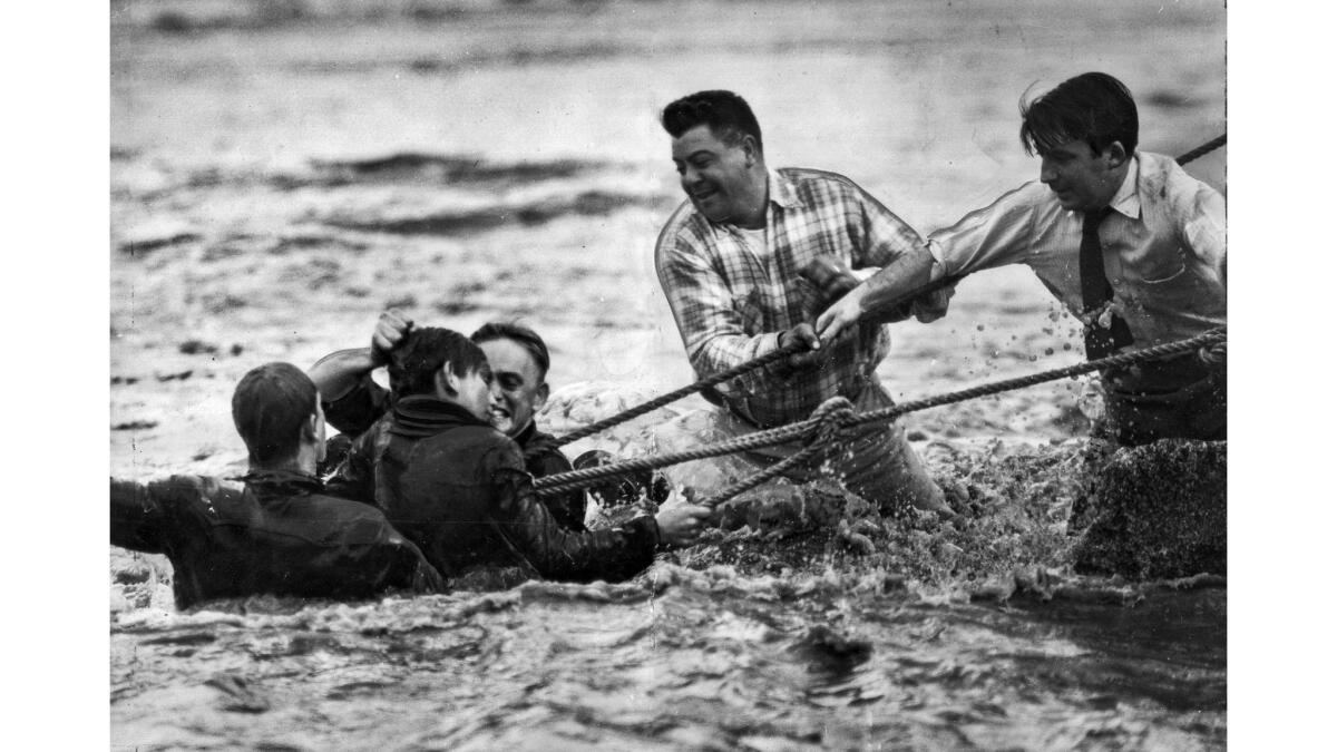 Jan. 23, 1952: Firefighter James Hassen lifts Jim Rossetto by the hair after the boy and firefigther John Reeves reached a bank during a rescue in the Los Angeles River.