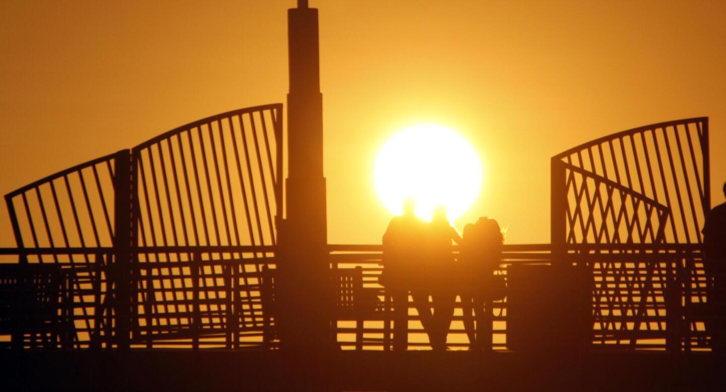 Tourists watch the sunset from the Hermosa Beach Pier. Voters will be asked to decide if the city should allow the return of oil drilling for the first time in more than 80 years.