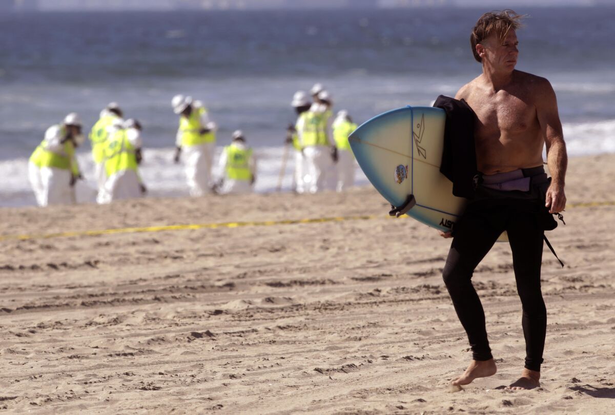  Surfer Eddie McKee walks near workers.