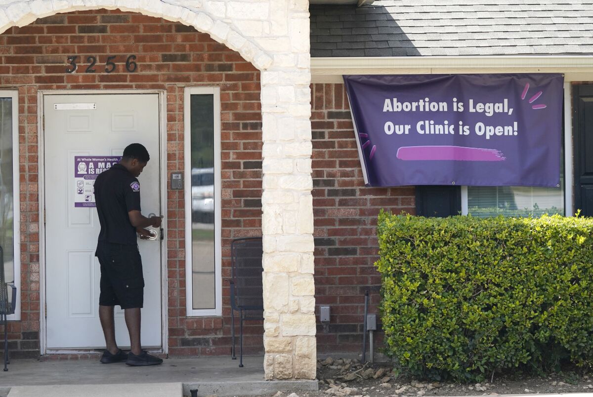 Un guardia de seguridad abre la puerta de la clínica Whole Woman's Health, en Fort Worth, Texas, el miércoles 1 de septiembre de 2021, la cual tiene un letrero que informa al público que está abierta. (AP Foto/LM Otero)
