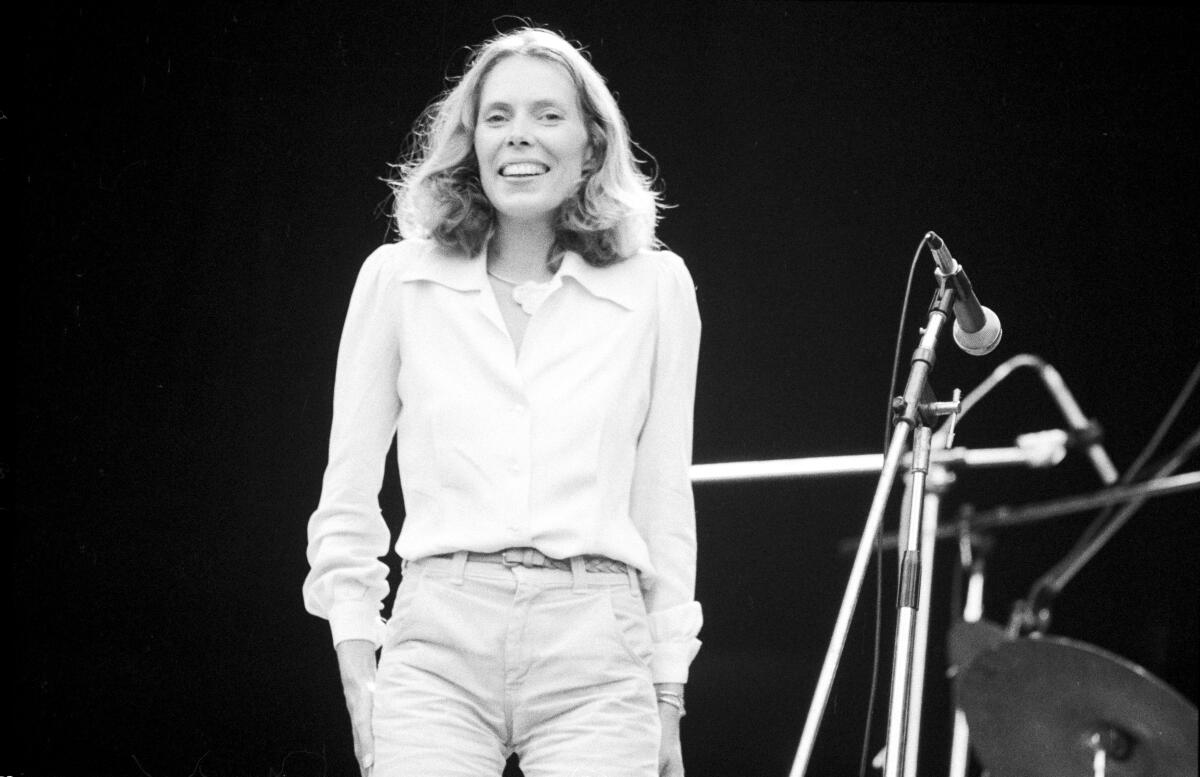 A black and white image of a woman standing onstage in front of a microphone