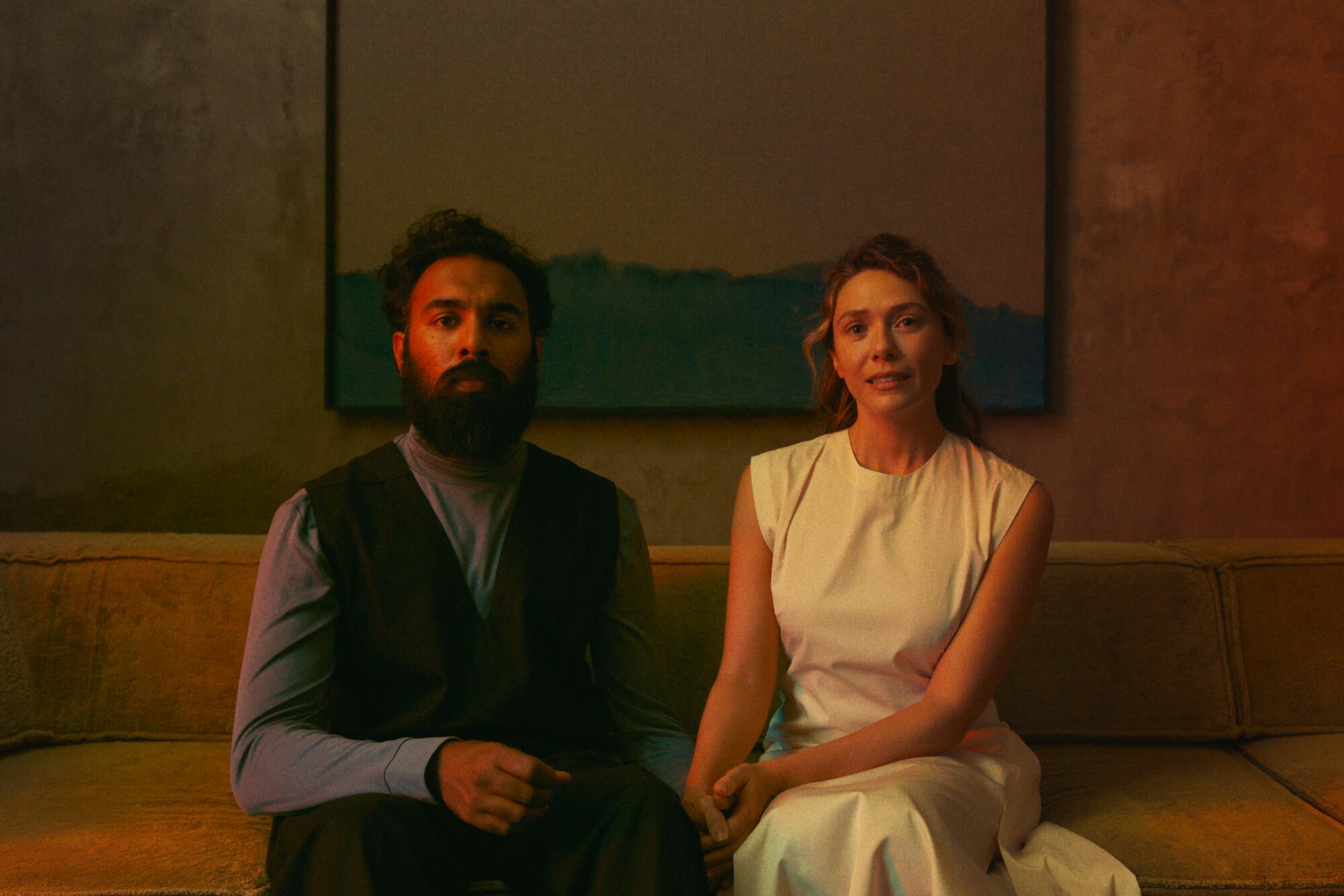A couple sits on a couch, being assessed.