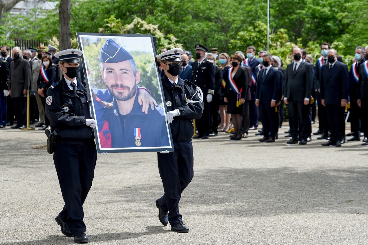 French police officers carry a portrait of police officer Eric Masson, killed last week in an apparent drug-related incident. During a national homage in Avignon, southern France, Tuesday, May 11, 2021. It was the latest of several attacks targeting French police that have angered police unions and become a political issue ahead of regional elections in June and next year's presidential election. France's prime minister is proposing tougher and faster punishment for people who attack police. (Nicolas Tucat, Pool via AP)