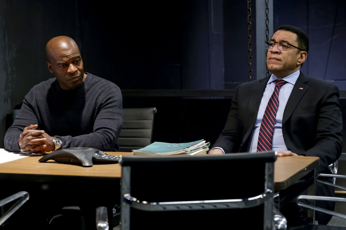 Two men seated at a conference room table.