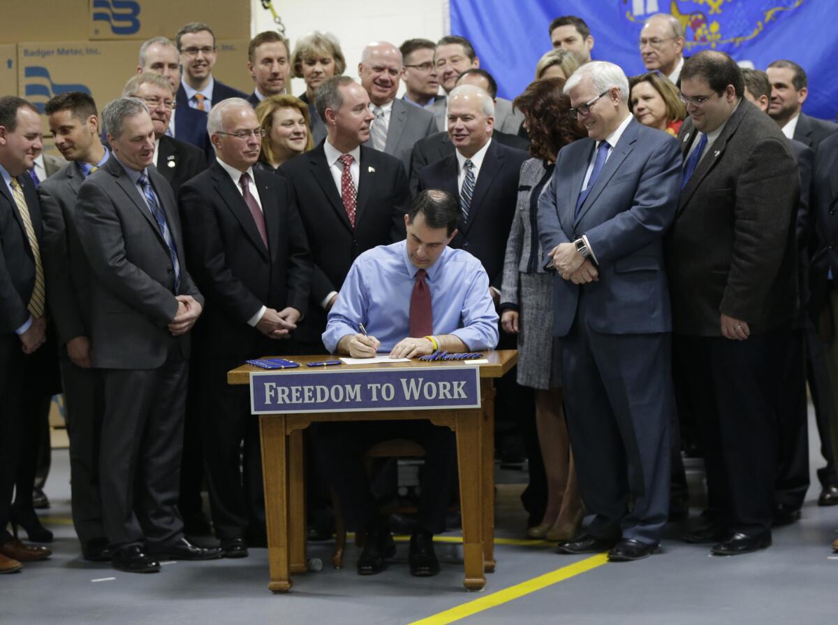 Then-Wisconsin Gov. Scott Walker signs a right-to-work bill in 2015. Democratic presidential candidates Elizabeth Warren and Bernie Sanders favor prohibiting such anti-union state laws.