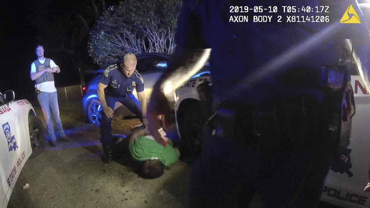 Police officers surround a man on the ground. 