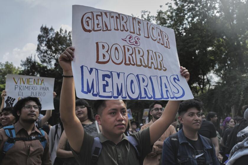 A demonstrator holds a sign that reads in Spanish, "To gentrify is to erase memories," during a protest against gentrification, as the increase in remote workers has risen prices and increased housing demand in neighborhoods like Condesa and Roma, in Mexico City, Friday, July 4, 2025. (AP Photo/Jon Orbach)