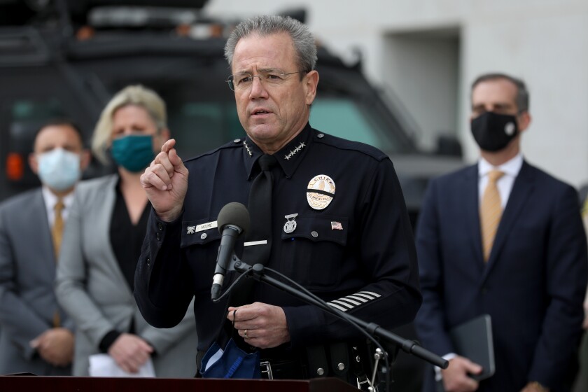 Los Angeles Police Department Chief Michel Moore discusses public safety preparedness as people stand behind him.