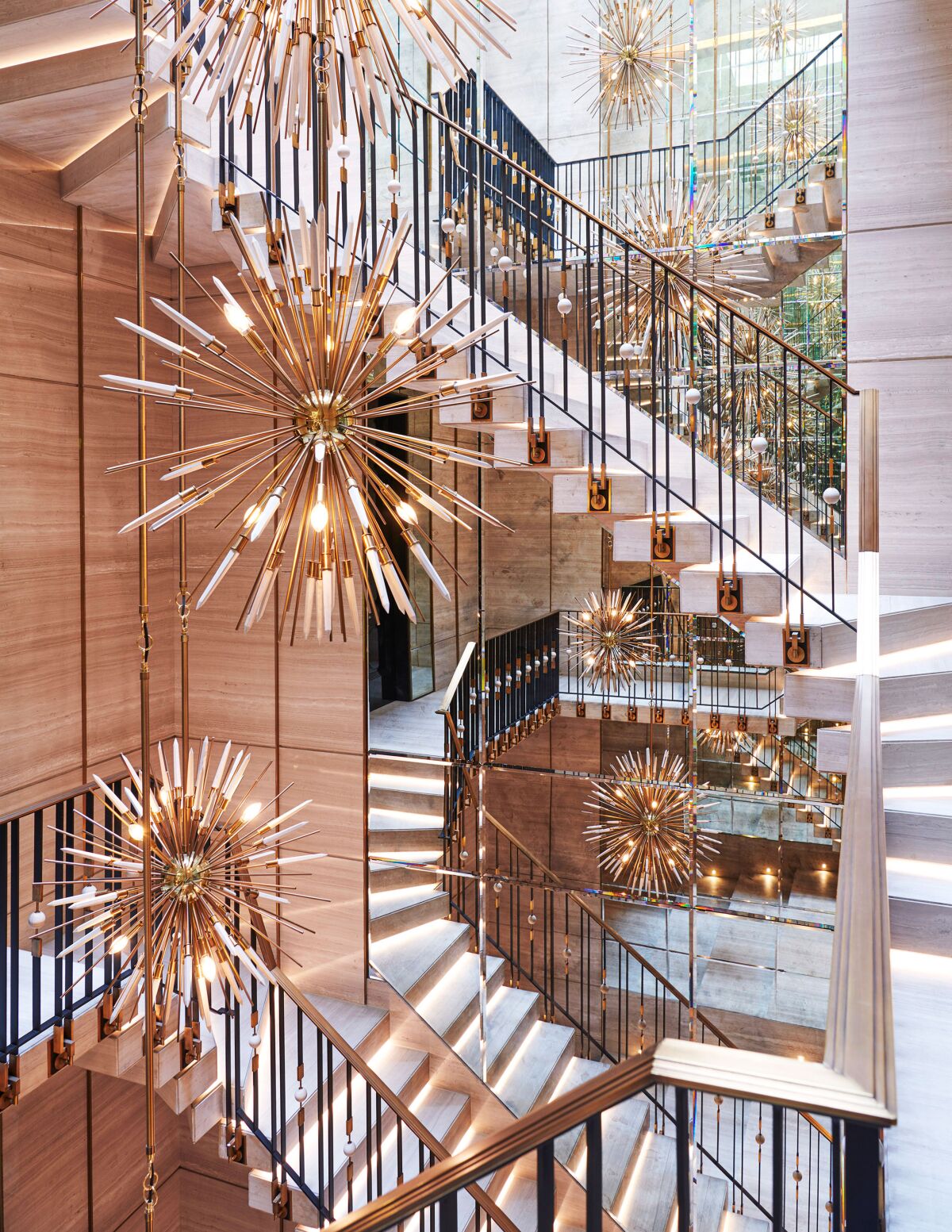 A suspended cantilevered block marble stair in Drake's Toronto mansion is adorned with chandeliers by Rafauli.